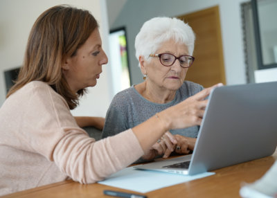 Elderly woman using laptop with help of homecarer